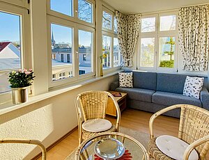 Wintergarten der Ferienwohnung Villa Fortuna mit Meerblick, Schlafcouch, Glastisch und Korbstühlen