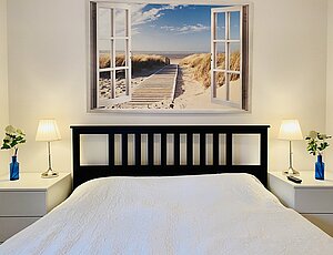 gemütliches Doppelbett mit maritimen Glasbild an der Wand