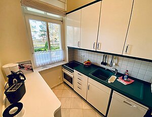 Separate Küche der Ferienwohnung 3 in der Villa Caprivi mit Backofen, Geschirrspüler, Ceranfeld, Kaffeemaschine in weiß-dunkelgrünem Farbkonzept. 