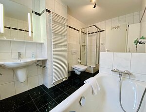 Badezimmer mit Dusche und Wanne in der Ferienwohnung Mine