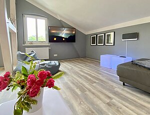 Modernes Wohnzimmer unterm Dach der Villa Anna in der Ferienwohnung 3/4 Takt mit großem TV 