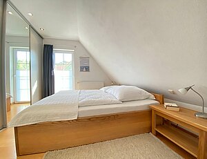 Schlafzimmer mit Holz-Doppelbett und großem Kleiderschrank im Ferienhaus Ostseekind