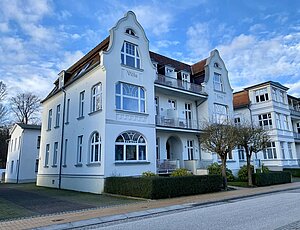     Die Villa Frieda, 1920 erbaute Bäderstilvilla in Bansin, präsentiert sich mit einer eleganten Fassade, die durch große Fenster, vorgezogene Veranden und verspielte Balkone geprägt ist. Die Vorderfront der Villa blickt auf das Meer, wodurch die Gäste einen schönen Seeblick genießen. Zu jeder Ferienwohnung gehört ein Stellplatz."