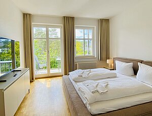 In der Ferienwohnung Krist, direkt am Strand von Ahlbeck, erwartet die Gäste ein freundliches Schlafzimmer mit Doppelbett, Balkonzugang und TV mit großem Doppelbett