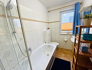 Badezimmer der Ferienwohnung Maris mit Badewanne und Duschabtrennung