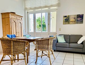 Lichtdurchflutetes Wohnzimmers der Ferienwohnung 5 der Villa Caprivi mit hölzernem Esstisch und Lederzweisitzer.