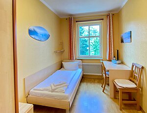 Gemütliches Schlafzimmer mit Einzelbetten und Schreibtisch