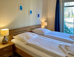 Das Schlafzimmer in der Ferienwohnung 11 der Residenz Bleichröder bietet ein gemütliches Doppelbett und einen TV.