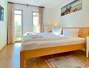 Modernes Schlafzimmer der Ferienwohnung 28 mit TV an der Wand und elegantem Holz