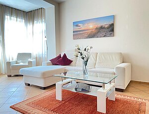 Ferienwohnung 1 Villa Jasmin Heringsdorf mit weißer Ledercouch und Couchtisch davor, Fernsehsessel und Teppich