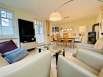 modernes Wohnzimmer mit Ledermöbeln in der TV-Ecke, großer Esstisch aus Holz und 6 Stühle, Kaminofen und offene Küchenzeile- ideal für Ihren Usedomurlaub